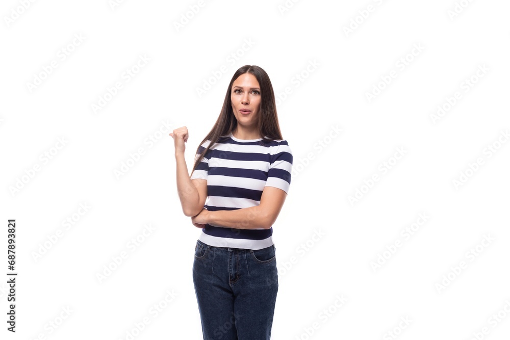 attractive young caucasian brunette woman in a striped t-shirt points with her hands to the advertising space on a white background with copy space attractive young caucasian brunette woman in a striped t-shirt points with her hands to the advertising space on a white background with copy space
