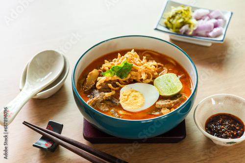 Northern Thai style curried noodle soup with beef and egg on wooden table