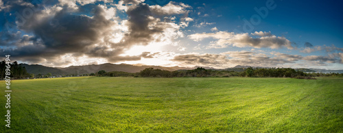 green meadow against the backdrop of mountains during sunrise New Zealand