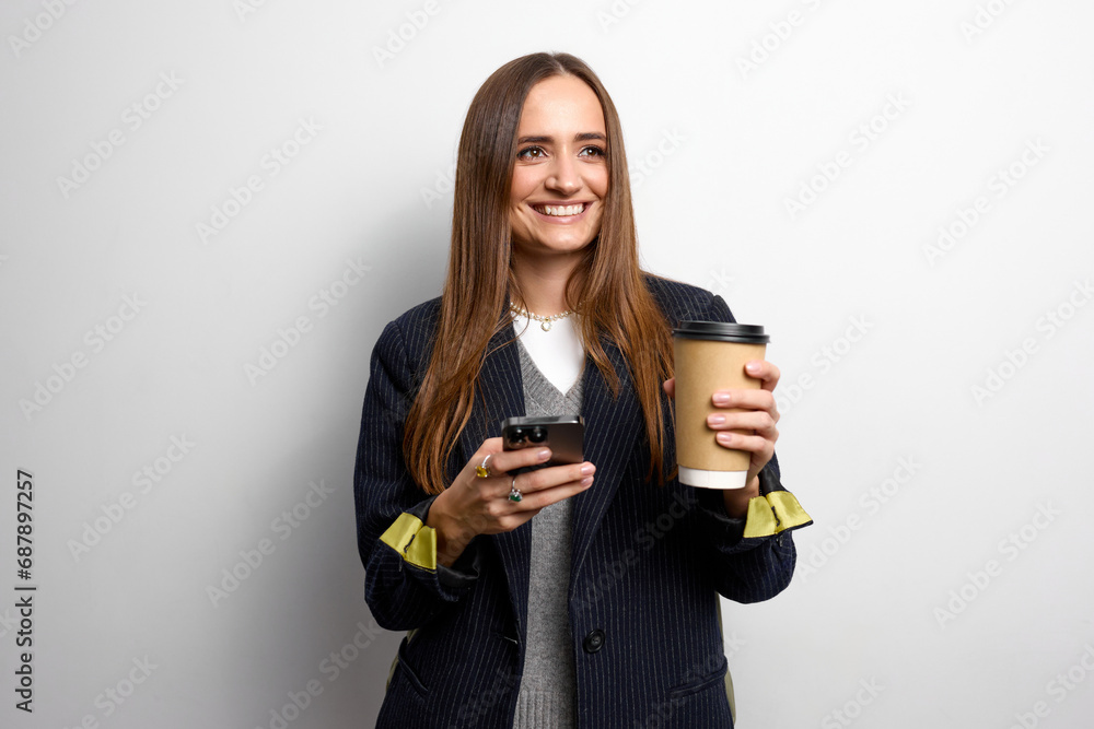 Stylish brown-haired young business woman dressed in a hairy jacket checks email on the device Stylish brown-haired young business woman dressed in a hairy jacket checks email on the device