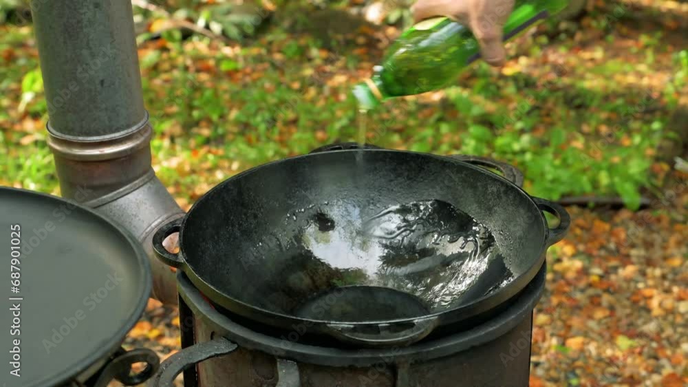 Kitchener lubricates with oil hot cast iron pan outdoors. 4k video footage Kitchener lubricates with oil hot cast iron pan outdoors. 4k video footage