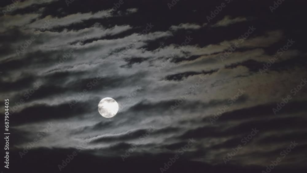 Beautifully shaped night clouds passing over the full moon