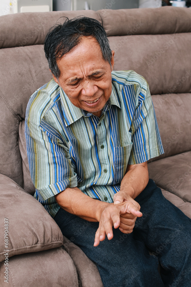 Fototapeta premium Elderly man experiences discomfort and pain in hands. Old man with finger pain, showcasing his actions of massaging his arthritic hand and wrist.