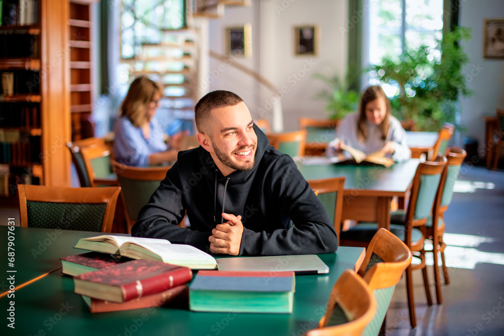 Handsome young man sitting in the university library and learning Handsome young man sitting in the university library and learning