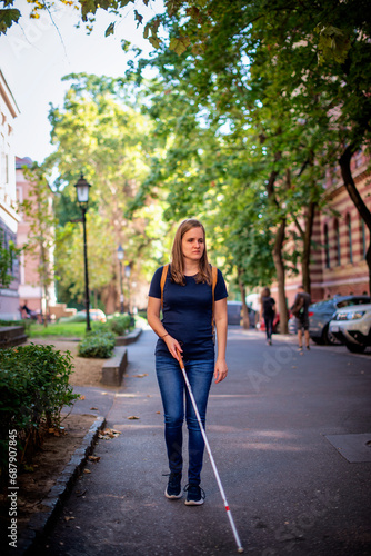 Full length of a blind woman with white cane walking on the city street