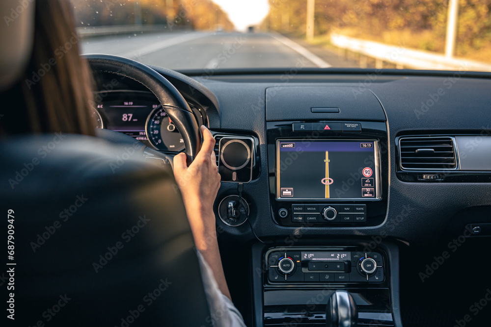 Woman driver hands on steering wheel inside car.