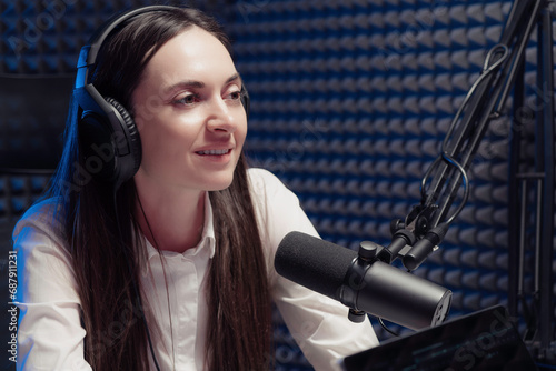 A woman podcaster in a white shirt, smiling as she shares stories during a live podcast in a professional studio photo