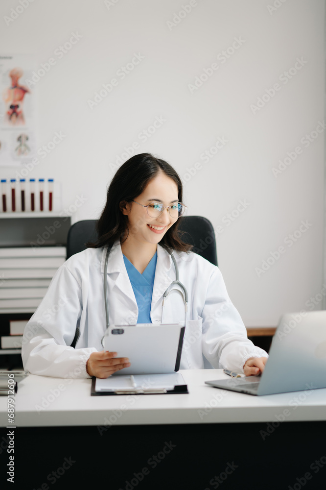 Beautiful physician doctor sit on table in office hospital. Attractive therapist female practitioner pharmacist smile and use tablet and laptop. after success work from treatment Beautiful physician doctor sit on table in office hospital. Attractive therapist female practitioner pharmacist smile and use tablet and laptop. after success work from treatment