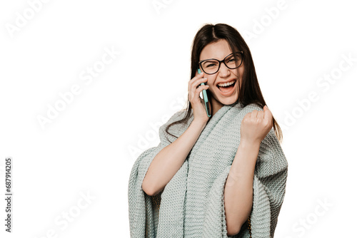 Photography Excited young girl clenches fist like winner  talks by phone received great news, wrapped in knitted blanket against transparent background, looks at camera