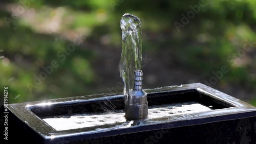 Close-up of a cool water fountain (pulpulak) against a backdrop of lush green trees and grass. photo