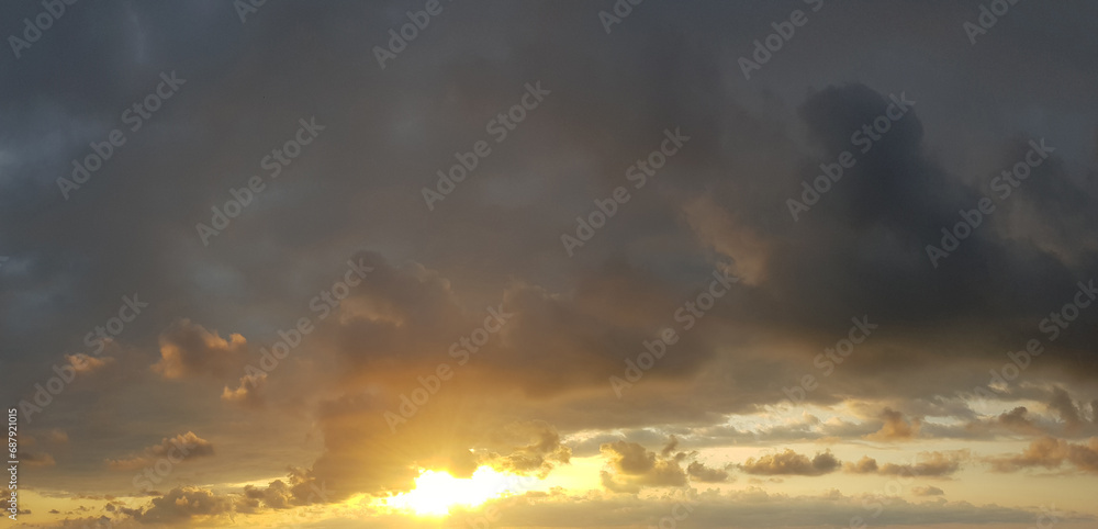 Dark storm cloud with golden sun on dramatic sunset sky