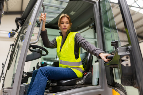 Female warehouse worker driving forklift. Warehouse worker preparing products for shipmennt, delivery, checking stock in warehouse.