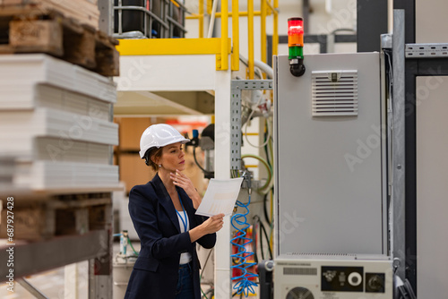 Female manager standing in modern industrial factory. Manufacturing facility with robotics and automation. Female leader, CEO in heavy industry, manufactury.