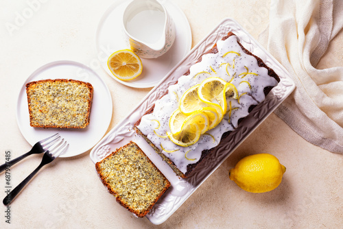 Top view of homemade breakfast. Sliced pound cake with lemon zest, sugar and lemon glaze, poppy seeds on a white plate and light background.