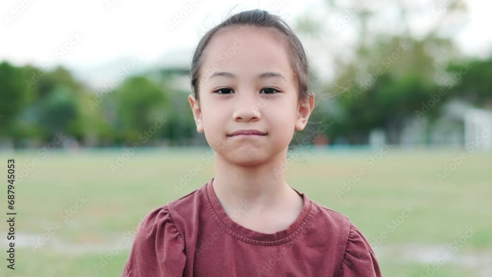 Close up face portrait of adorable Asian kid girl in beautiful park shows calmness and peaceful expression. It shows concept of thoughtful child with still and concerning face in carefree summer. Close up face portrait of adorable Asian kid girl in beautiful park shows calmness and peaceful expression. It shows concept of thoughtful child with still and concerning face in carefree summer.