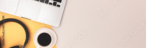 Banner with headphones, cup of black coffee and laptop on a gray and gold background. Online education concept. photo