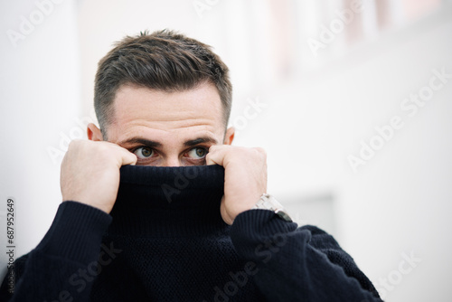 Close-up of a mysterious man partially hiding his face behind a black turtleneck photo