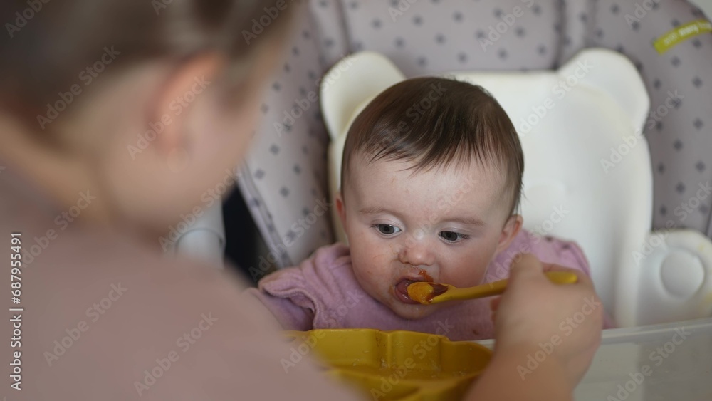 baby newborn eats. happy family dream weaning concept. dirty mess baby girl eating vegetables. baby daughter eats on a feeding chair indoors dirty face. naughty dirty babe indulges while feeding . baby newborn eats. happy family dream weaning concept. dirty mess baby girl eating vegetables. baby daughter eats on a feeding chair indoors dirty face. naughty dirty babe indulges while feeding .