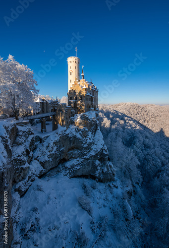 Fairytale castle “Lichtenstein“ with frosted trees near Honau Reutlingen on a cold sunny december morning. Winter wonderland in Baden-Württemberg, southern Germany. Seasons greetings atmophere.
