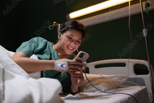 a beautiful young girl in the hospital is being treated after a severe flu in the hospital holding a phone in her hands chatts with family in group.