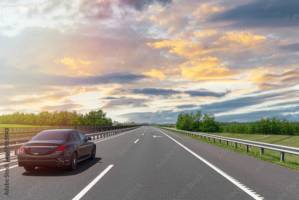 Dark car on a freeway in a beautiful area. Dark car on a freeway in a beautiful area.
