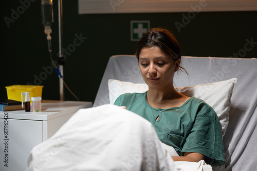 Serious concentrated woman in hospital ward in bed recovers after accident.