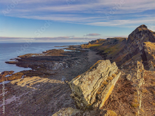 The rocky coast of the Barents Sea. Beautiful view of the rocks and the coast of the Rybachy and Sredny peninsulas, Murmansk region, Russia. The landscape is the harsh beauty of the north. photo