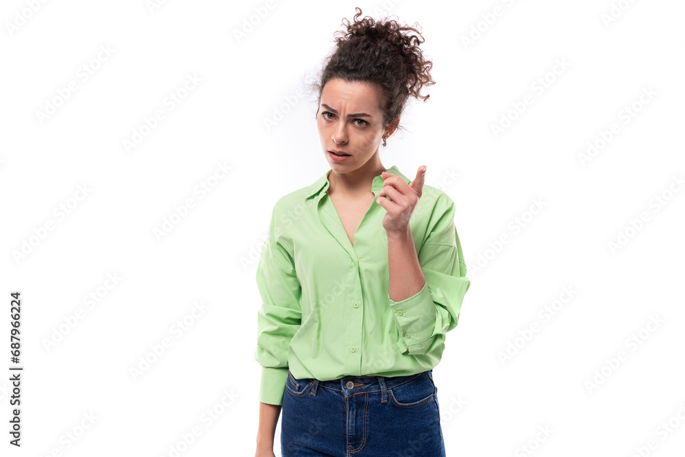 young brunette curly slender female model dressed in a light green shirt points with her index finger young brunette curly slender female model dressed in a light green shirt points with her index finger