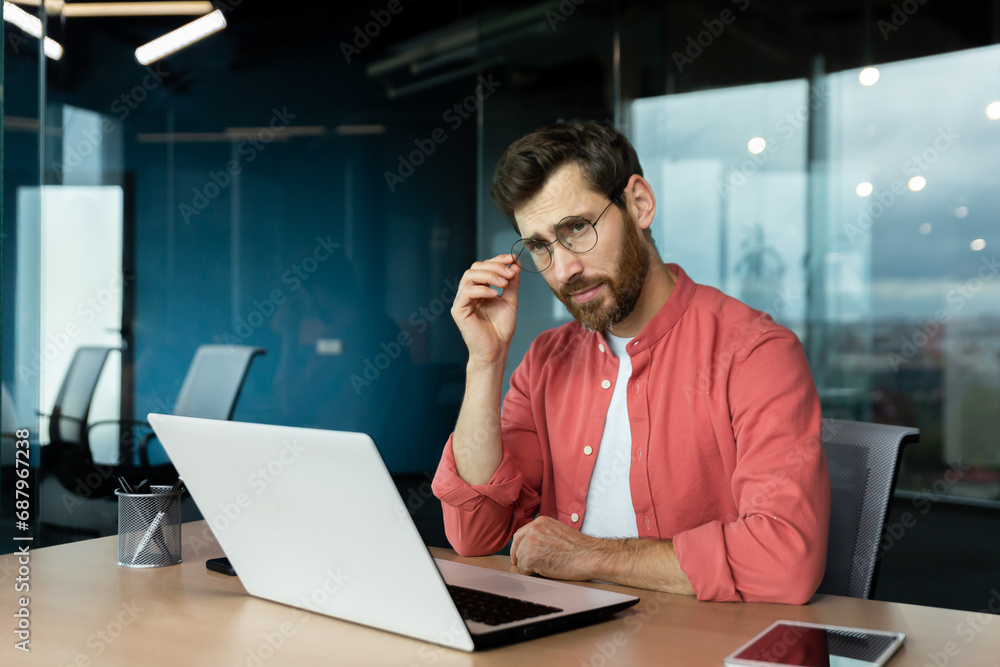 Sad unhappy and disappointed man at workplace inside office, businessman in shirt and glasses unhappy with achievement results, accountant with bad statistical report. Sad unhappy and disappointed man at workplace inside office, businessman in shirt and glasses unhappy with achievement results, accountant with bad statistical report.