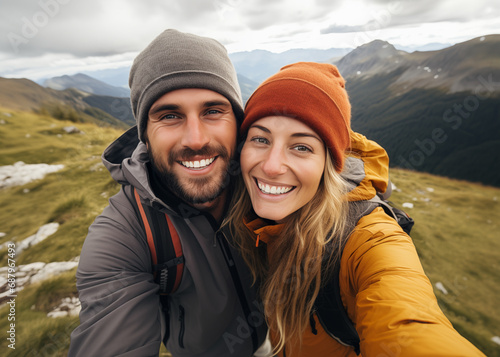 Cute couple of young people smiling and enjoying vacations trip together walking and trekking in mountains. Cheerful man and woman in love taking selfie