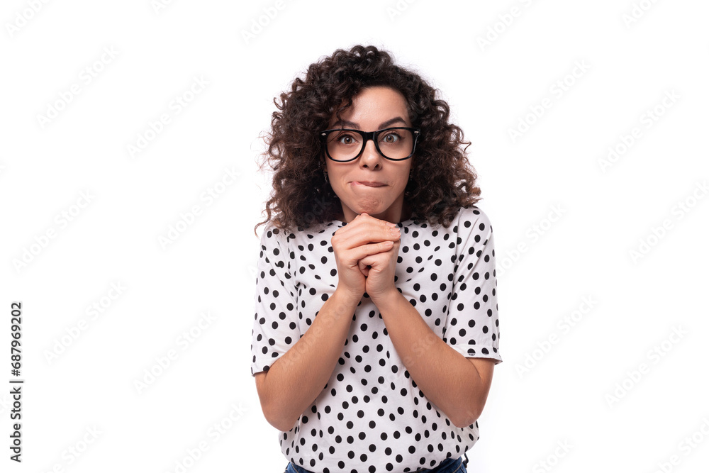 a young woman with a curly hairstyle dressed in a summer polka dot print blouse folded her hands in front of her and thought a young woman with a curly hairstyle dressed in a summer polka dot print blouse folded her hands in front of her and thought