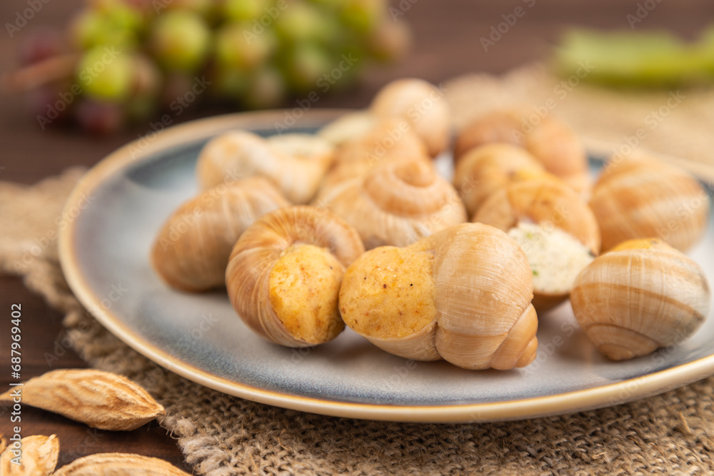 Grape (Burgundy) snails with butter and cheese on brown wooden, side view, selective focus Grape (Burgundy) snails with butter and cheese on brown wooden, side view, selective focus