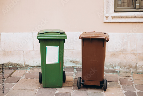 Waste separation, two different color trash can bins standing in front of the house in public along street. Help to reduce waste, Help global warming. Garbage trash bins for waste segregation.