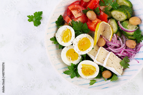 Breakfast. Greek salad and boiled eggs. Fresh vegetable salad with tomato, cucumbers, olives, arugula and cheese. Trendy food. Top view, flat lay