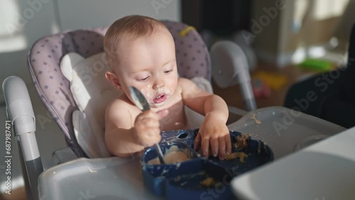 baby dirty eats. happy family a child toddler concept. baby dirty sitting messing with food lifestyle at the table for feeding in the kitchen. grimy toddler in the kitchen photo