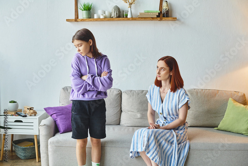 Canvastavla offended teenage girl standing with folded arms near upset mother sitting on cou