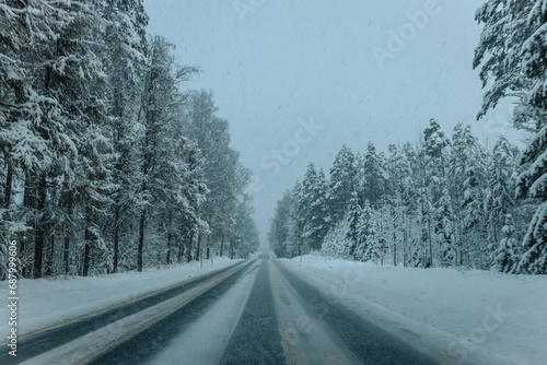 A Wintry Path Through a Chilly Forest with Snow Covered Trees. Winter road through snowy forest, tree lined and cold temperature.