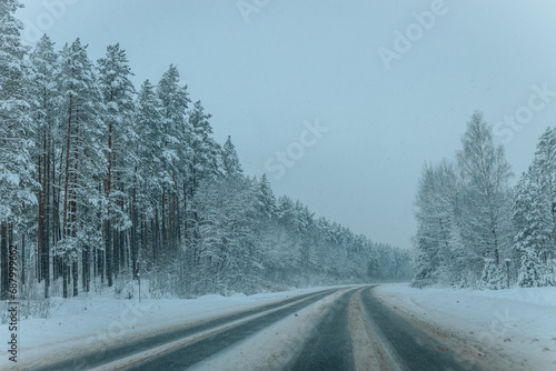 A Wintry Path Through a Chilly Forest with Snow Covered Trees. Winter road through snowy forest, tree lined and cold temperature. © Emvats