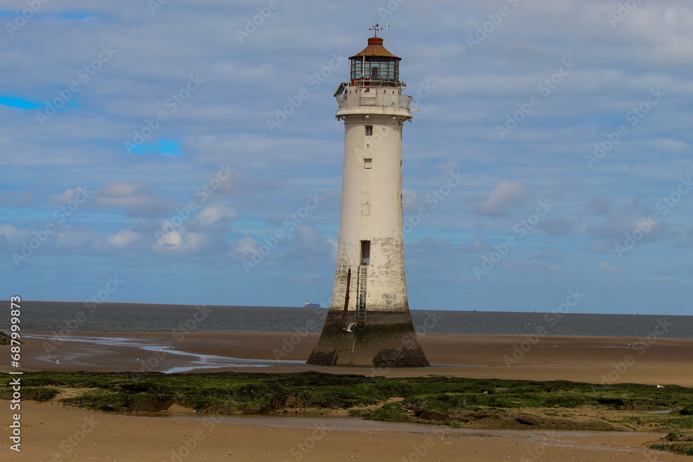 An historic Lighthouse on the beach with the sea in the background.