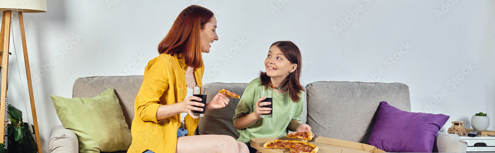 cheerful mother and teenage daughter with pizza and soda on cozy couch in living room, banner cheerful mother and teenage daughter with pizza and soda on cozy couch in living room, banner