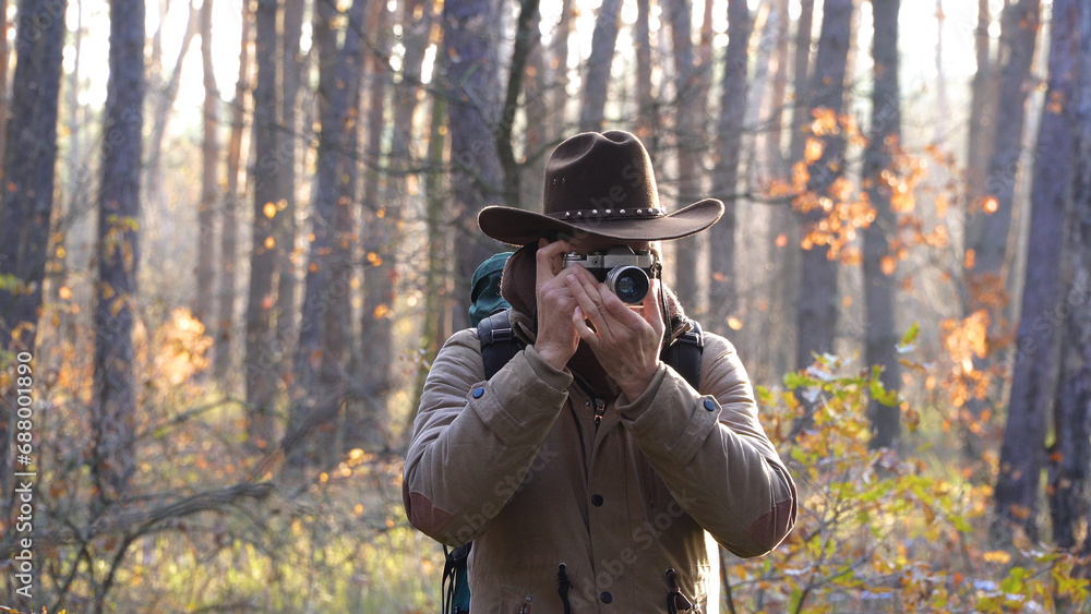 A man in a hat takes pictures in the forest A man in a hat takes pictures in the forest
