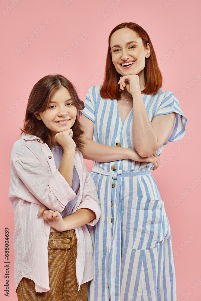 cheerful mother and preteen daughter in stylish casual clothes posing and smiling at camera on pink cheerful mother and preteen daughter in stylish casual clothes posing and smiling at camera on pink