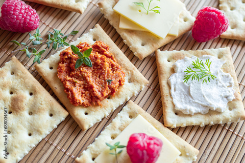 Various kind of salty crackers with vegan meat and vegan cream cheese decorated with fresh herbs and raspberries. Vegan food concept.