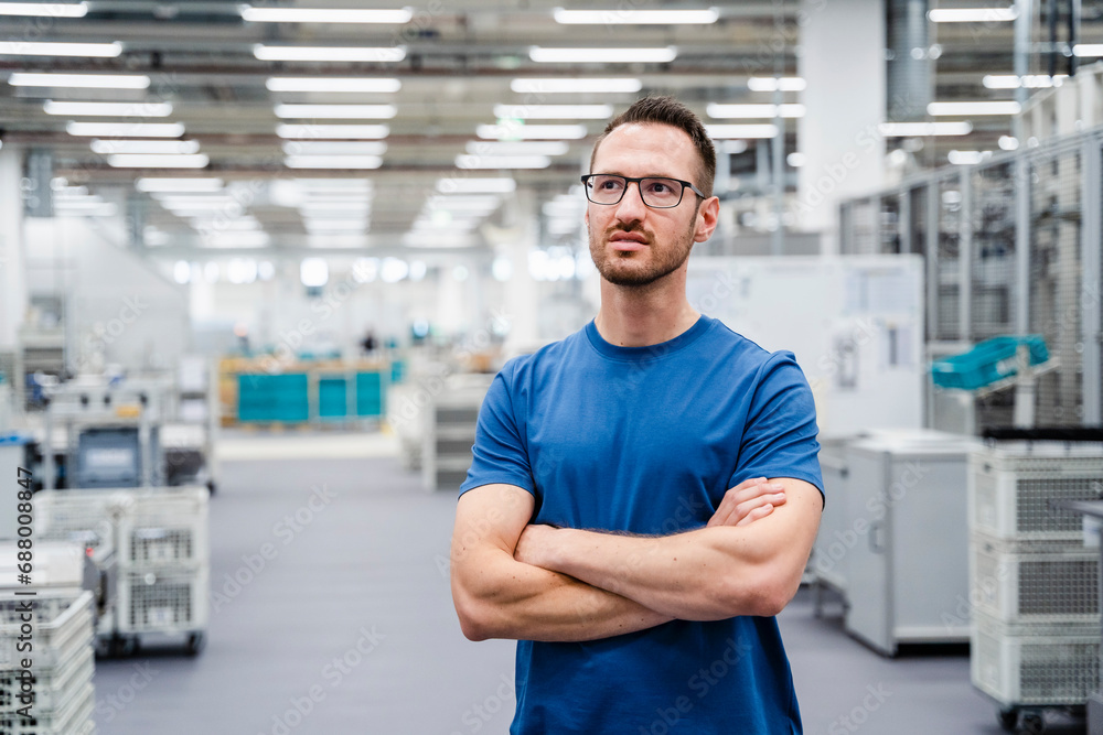 Employee standing in a factory with arms crossed Employee standing in a factory with arms crossed