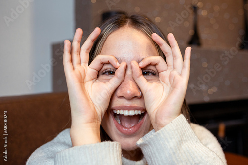 Cheerful woman gesturing OK sign over face at home photo
