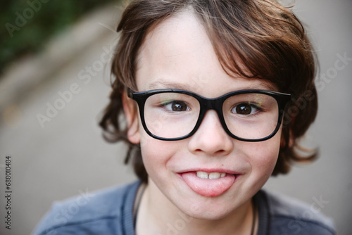 Playful boy wearing eyeglasses sticking out tongue photo