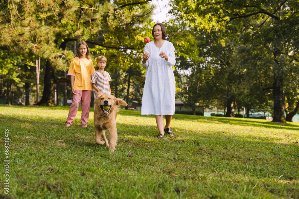 Family spending leisure time with dog running on grass at park Family spending leisure time with dog running on grass at park