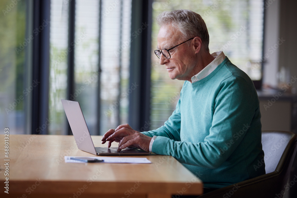 Senior man using laptop at table at home
