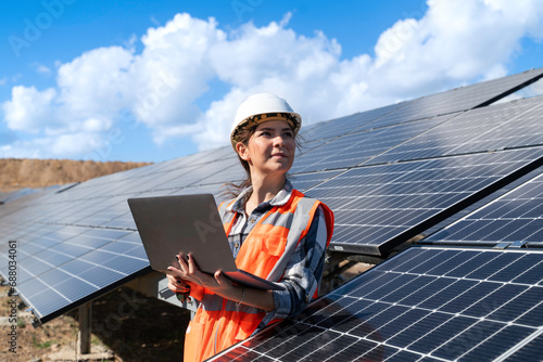 Young engineer inspect installation of solar panels installed check  with blueprint on the field, with recording inspection data on pc.
