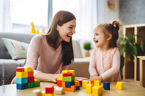 Happy mother and little girl playing with blocks on the floor.